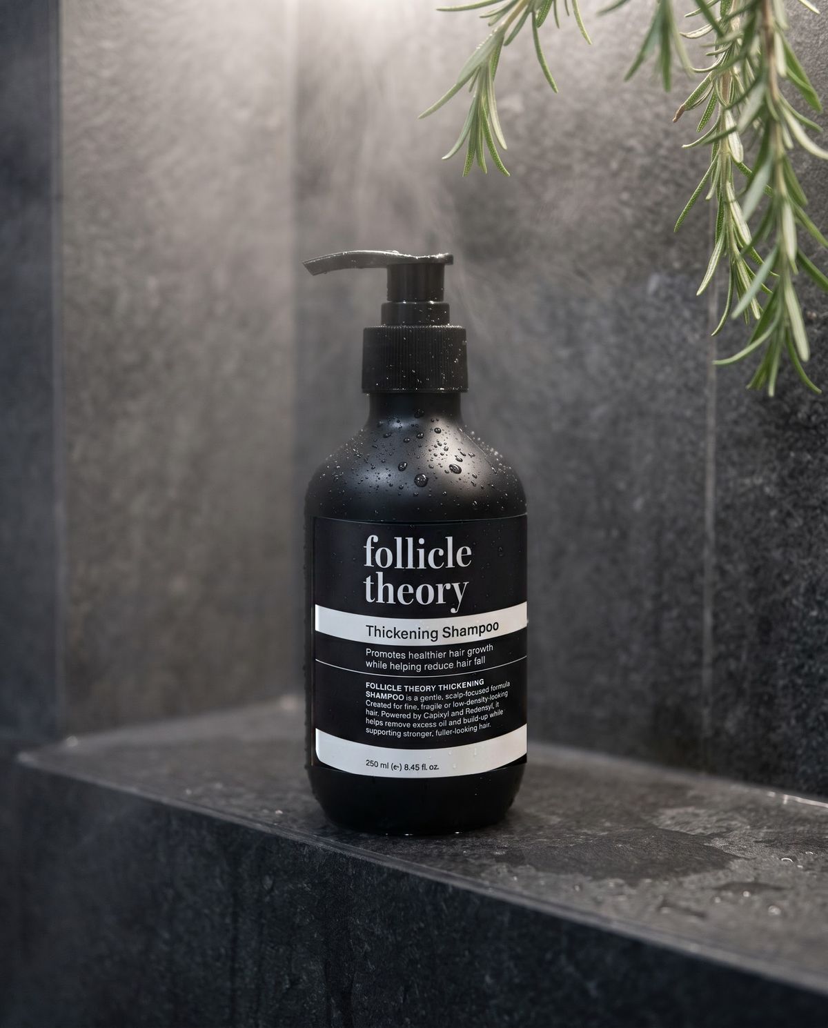 follicle theory Thickening Shampoo in a stone shower niche with a sprig of rosemary
